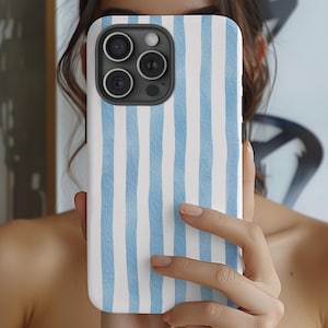 May include: A white and light blue striped phone case. The case has a vertical watercolor stripe design. The phone case is covering the back of a smartphone with multiple camera lenses.