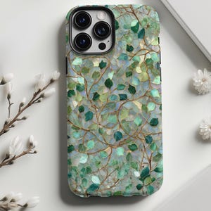 May include: A smartphone case with a nature-inspired design. The case features a pattern of green and blue leaves and vines against a light background. The case has a glossy finish and a camera cutout.