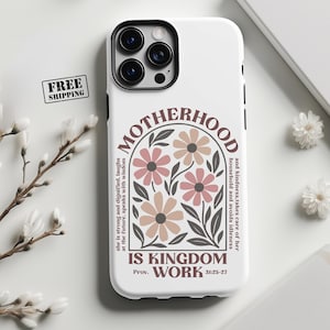 May include: White phone case with a black camera module and a floral design. The case features the word "MOTHERHOOD" and the text "IS KINGDOM WORK" with a Bible verse reference. The design includes pink and tan flowers.