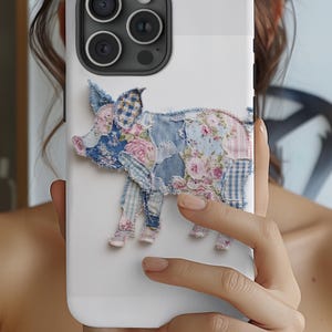 May include: White phone case featuring a patchwork pig design. The pig is crafted from various fabrics, including denim and floral patterns in shades of blue, pink, and white. The case has a glossy finish and a camera cutout.