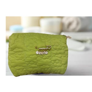 May include: A lime green quilted makeup bag with a gold safety pin charm that says "NURSE" in white letters.