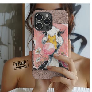 May include: A phone case featuring a whimsical illustration of a goose blowing a bubblegum bubble. The case has a pink background with daisies and a glittery rose gold border. The goose has a yellow beak and is surrounded by a pink bubble.