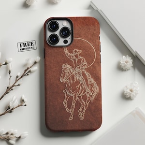 May include: A brown phone case with a light beige line drawing of a cowboy on a horse, roping a steer. The case has a textured background and a black border. The camera cutout is visible.