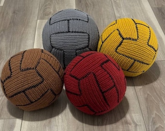 May include: Four crocheted soccer balls in different colors: gray, brown, yellow, and red. Each ball has black stitching.