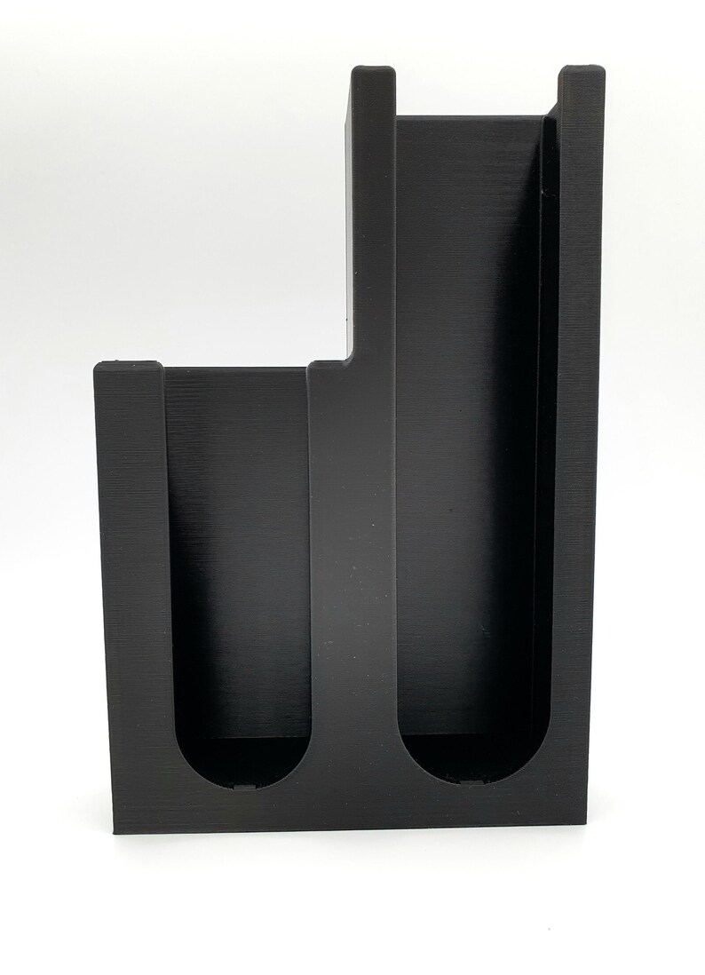 May include: Black plastic organizer with three slots for holding items like pens, pencils, or paintbrushes.