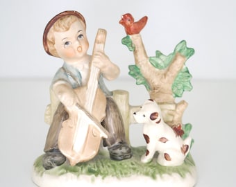 Figura de cerámica vintage de CEDO: Niño tocando el violonchelo con perro y pájaro. Fabricada en Corea.