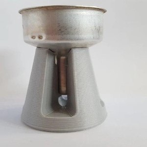 May include: A grey plastic stand with a metal coffee filter on top. The stand has a hole in the centre for the filter to sit on.