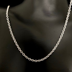May include: A silver-colored chain necklace with a classic cable link design. The necklace is displayed on a black mannequin, showcasing the chain's polished finish and the individual links that make up the necklace.
