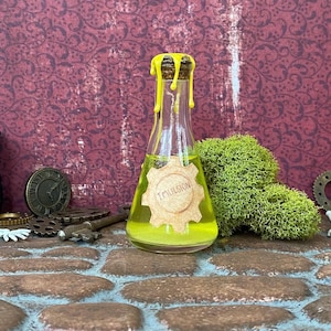 May include: A clear glass bottle with a cork stopper and yellow wax drips. The bottle contains a yellow liquid and a label that reads "Imulsion". The bottle is surrounded by decorative elements, including a clock and gears.