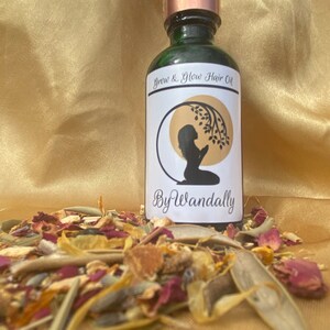Pode incluir: Uma garrafa de vidro verde com um conta-gotas de cobre. A garrafa tem um r&oacute;tulo branco com o texto "Grow & Glow Hair Oil" e "By Wandally". O r&oacute;tulo tamb&eacute;m apresenta uma silhueta de uma pessoa com as m&atilde;os juntas em ora&ccedil;&atilde;o.