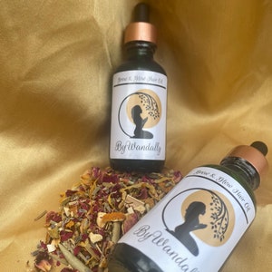 Pode incluir: Duas garrafas de vidro verde escuro com conta-gotas dourados e etiquetas brancas. As etiquetas apresentam uma silhueta de uma pessoa com um ramo de &aacute;rvore e o texto "Grow & Glow Hair Oil" e "By Wandally". As garrafas est&atilde;o sobre uma superf&iacute;cie de tecido dourado com ervas e flores secas.