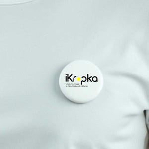 May include: White round button with black text that reads "ikropka your partner in printing and design" with a yellow dot.