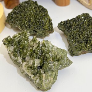 May include: Three green and clear crystal clusters. The crystals are rough and have a natural, earthy look.