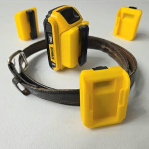 May include: A yellow DeWalt 20V battery and three yellow battery holders. The battery holders are attached to a brown leather belt.