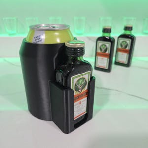 May include: Black plastic drink holder with a can of soda and a small bottle of Jagermeister. The can has a label that says "Variety Pack Exclusive".