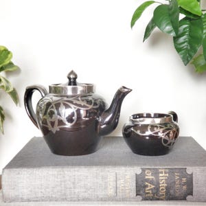 Art Nouveau Black Ceramic Silver Overlay Teapot And Creamer, Early 1900s