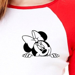 May include: A white and red baseball t-shirt with a black and white cartoon image of Minnie Mouse peeking over the top of the shirt.