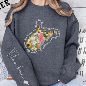 May include: Dark heather grey sweatshirt with a floral design of the state of West Virginia. The text "Take me home" is written on the left sleeve.
