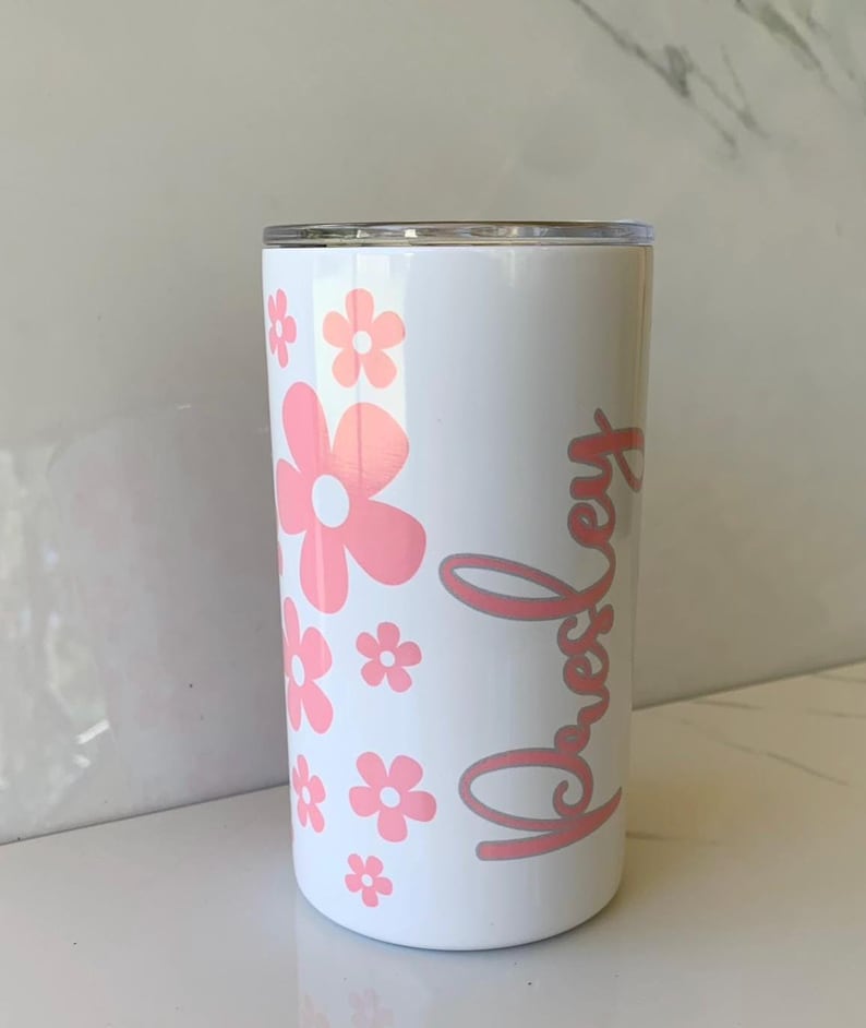 May include: White tumbler with a pink floral design and the name "Presley" written in pink cursive.