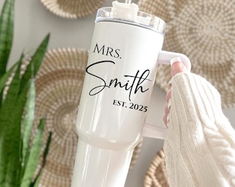 May include: White stainless steel tumbler with a black handle and lid. The tumbler has the text "MRS. Smith EST. 2025" printed on the side.
