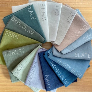 May include: A color chart of 14 fabric swatches in various shades of green, blue, brown, and gray. The swatches are arranged in a circle and labeled with names like "Kale", "White", "Oat", "Fog", "Sand", "Sky", "Slate", "Dark Olive", "Fern", "Forest", "Sage", "Lavender", "Dusty Blue", "Indigo Blue", and "Navy".