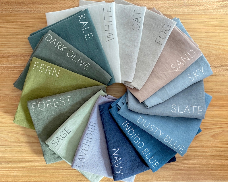 May include: A color chart of 14 fabric swatches in various shades of green, blue, brown, and gray. The swatches are arranged in a circle and labeled with names like "Kale", "White", "Oat", "Fog", "Sand", "Sky", "Slate", "Dark Olive", "Fern", "Forest", "Sage", "Lavender", "Dusty Blue", "Indigo Blue", and "Navy".