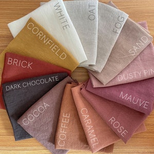 May include: A collection of 14 fabric swatches in various shades of brown, pink, and beige. The swatches are arranged in a circle and labeled with names like "White", "Oat", "Fog", "Sand", "Dusty Pink", "Mauve", "Rose", "Caramel", "Coffee", "Cocoa", "Dark Chocolate", "Brick", and "Cornfield".