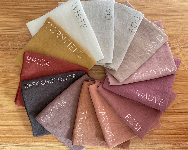 May include: A collection of 14 fabric swatches in various shades of brown, pink, and beige. The swatches are arranged in a circle and labeled with names like "White", "Oat", "Fog", "Sand", "Dusty Pink", "Mauve", "Rose", "Caramel", "Coffee", "Cocoa", "Dark Chocolate", "Brick", and "Cornfield".