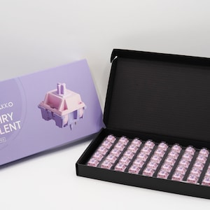 May include: A box of Akko Fairy Silent 65g mechanical keyboard switches. The box is purple and features a close-up image of a single switch. The box is open and reveals a tray of 65 pink and purple switches.