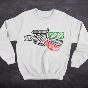 May include: White sweatshirt with a black and white outline of an eagle head with red and green accents. The eagle head is a stylized design with geometric patterns.