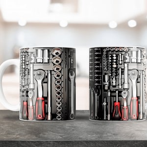May include: Two white ceramic mugs with a black and silver design of various tools, including wrenches, screwdrivers, and sockets. The mugs have a red accent on the handles.