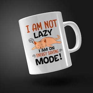 May include: White ceramic mug with a cartoon cat sleeping and the text "I am not lazy I am on energy saving mode!"