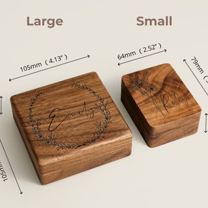 May include: Two wooden ring boxes, one large and one small. The large box is 4.13 inches wide and 1.5 inches tall. The small box is 2.52 inches wide and 1.22 inches tall. Both boxes have engraved names on the top.