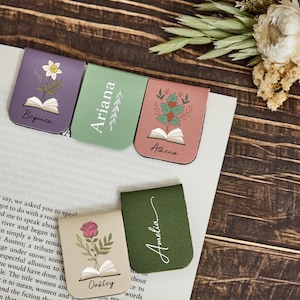 May include: Five magnetic bookmarks in purple, light green, pink, beige, and dark green. Each features a printed illustration of a flower emerging from an open book and a name: Beyonca, Ariana, Athena, Oakley, and Amelia, with decorative leaf accents.