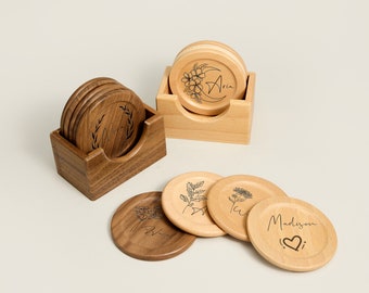 May include: Set of six wooden coasters with personalized names and floral designs. The coasters are in a wooden holder. The names on the coasters are Aria, Madison, and two others.