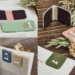 May include: A collection of magnetic bookmarks featuring various solid colors including sage green, dusty pink, navy blue, and olive green. Each bookmark displays a small illustration of an open book with a floral sprig emerging from the pages.