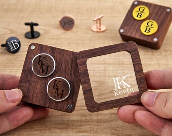 May include: Wooden cufflinks and a matching box with personalized initials and names. The cufflinks are silver and brown, with the initials "KM" engraved. The box has a clear window with the name "Kevin" engraved.