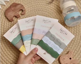 May include: Four rectangular cards labeled A Few Little Notes by Leylapet Studio, each featuring three wavy silicone bands in various pastel and muted colors. The bands are personalized with names like Avery Huang, Chloe Cooper, and Phoenix Cooper.