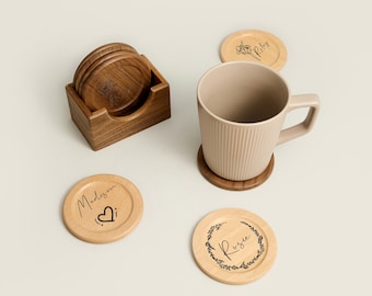 May include: Set of six wooden coasters with floral designs and personalized names, including "Rosie", "Madison", and "Riley". The coasters are in a wooden holder and one coaster is under a beige mug.