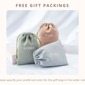 May include: Three drawstring pouches in pink, green, and gray. The pouches are made of a soft, fabric material.  FREE GIFT PACKINGS is written at the top of the image. *Please specify your preferred color for the gift bag in the order note is written at the bottom of the image.