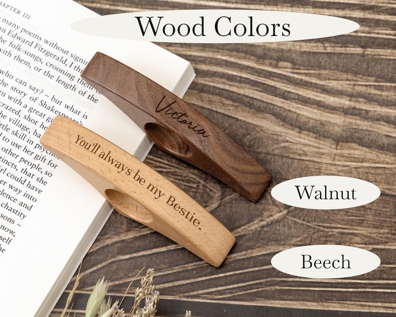 May include: Two wooden book page holders, one walnut and one beech, with engraved text. The walnut holder says "Victoria," and the beech holder says "You'll always be my Bestie." The image also shows the words "Wood Colors," "Walnut," and "Beech."