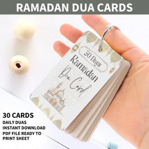 Puede incluir: Un conjunto de 30 tarjetas de Dua de Ramadán imprimibles con un diseño blanco y dorado. Las tarjetas presentan una ilustración de una mezquita y el texto "30 días Ramadán Dua Card".