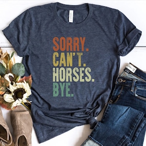 May include: A navy blue t-shirt with a vintage-style graphic that reads "SORRY. CAN'T. HORSES. BYE."