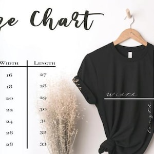 Może przedstawiać: Czarny t-shirt na drewnianym wieszaku z tabelą rozmiar&oacute;w zawierającą tekst Size Chart, Size, Width i Length. Tabela przedstawia wymiary w calach dla rozmiar&oacute;w od XS do 3XL, od 16 do 28 cali szerokości oraz od 27 do 33 cali długości.
