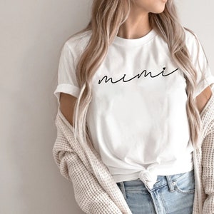May include: White t-shirt with the word "mimi" written in cursive on the front.