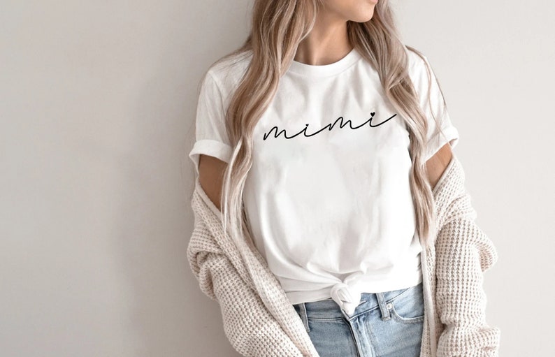 May include: White t-shirt with the word "mimi" written in cursive on the front.