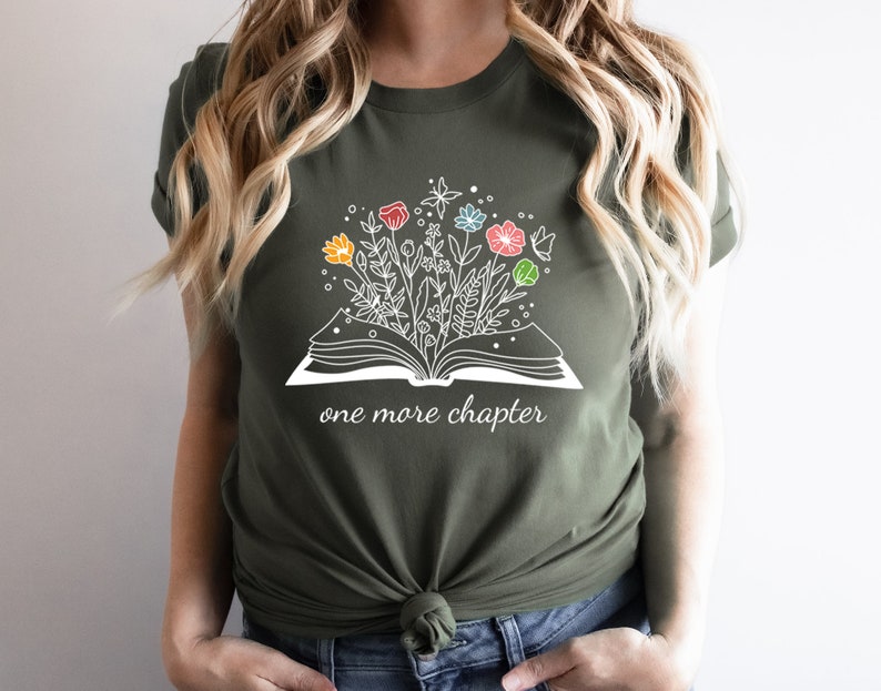 May include: A green t-shirt with a white graphic of an open book with flowers growing out of it. The text "one more chapter" is printed below the book.