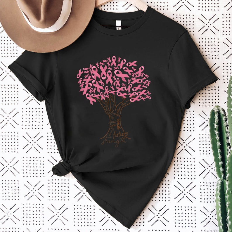 May include: A black short-sleeved t-shirt featuring a graphic of a tree where the leaves are composed of pink awareness ribbons. The trunk and branches contain the words cure, hope, faith, grace, fighter, together, future, and strength.
