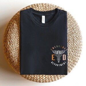 May include: Black t-shirt with a white graphic of a medical symbol and the text "Emergency Department" in a circle.
