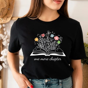 May include: Black t-shirt with a white graphic of an open book with flowers growing out of it. The text "one more chapter" is below the book.
